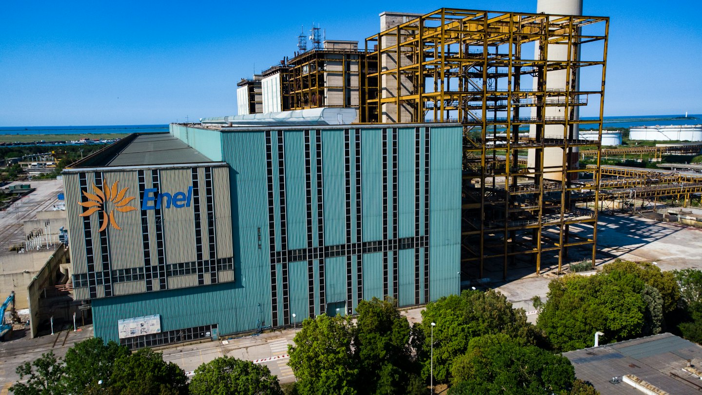 Central eléctrica de Enel con construcción y el mar de fondo.