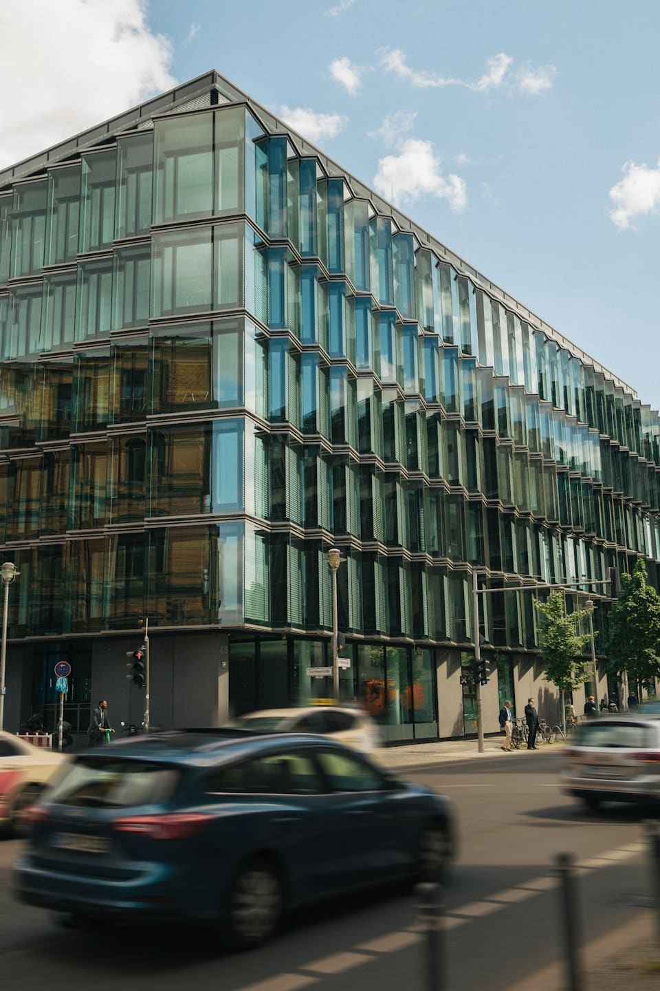 Edificio de oficinas moderno de cristal en una intersección concurrida de la ciudad.
